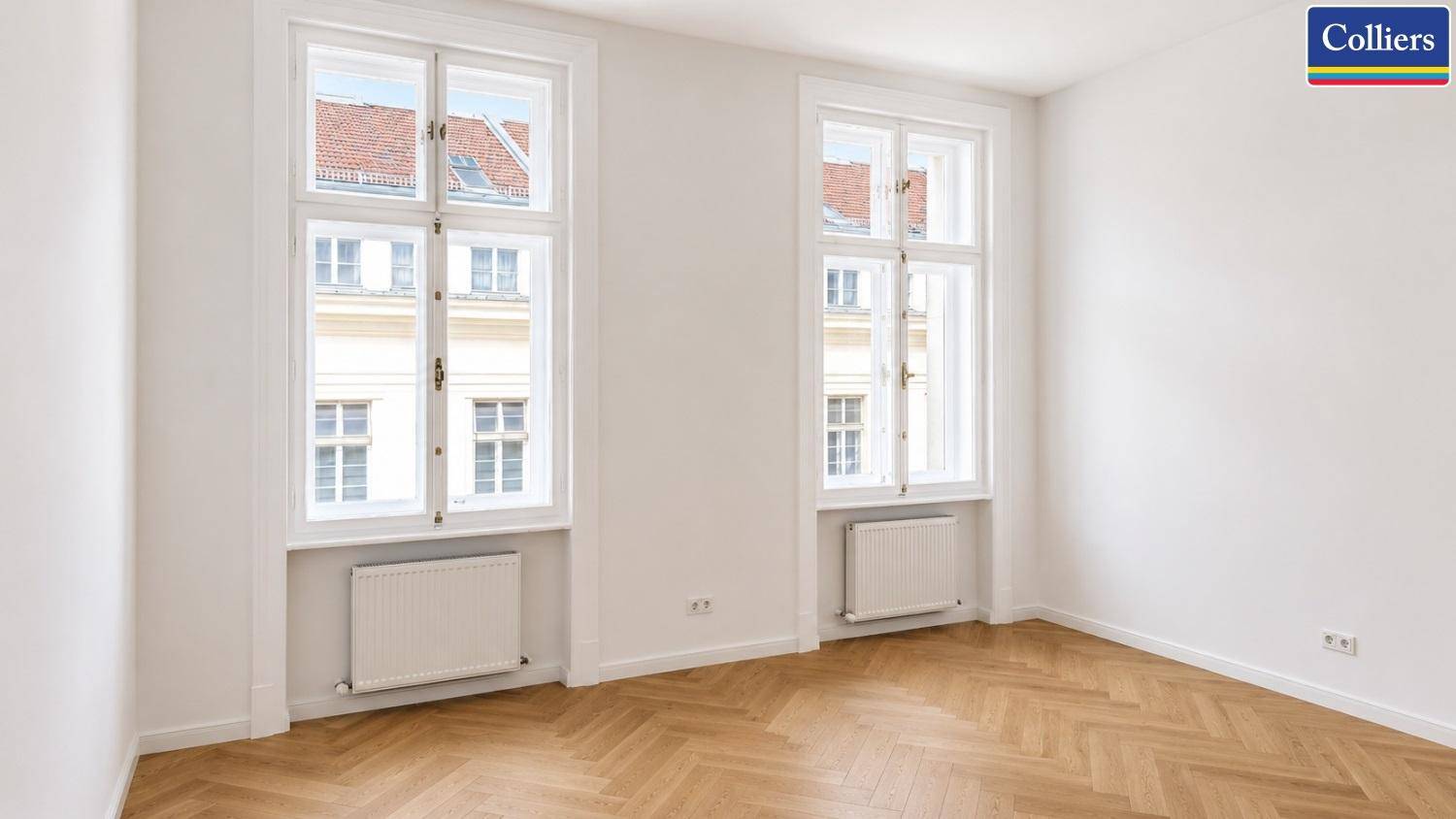 Heller Raum mit zwei hohen Fenstern und Fischgrätparkett, ideal als Büro oder Arbeitszimmer nutzbar.