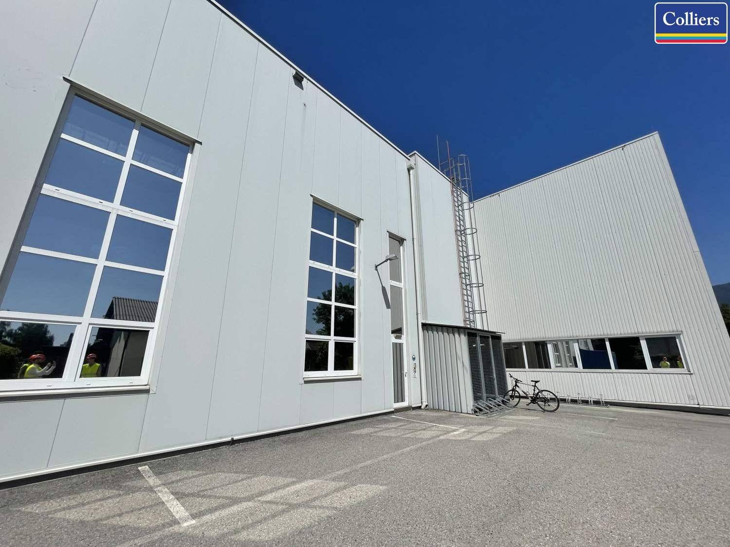 Industrielle Fassade des Gebäudes mit hohen Fenstern, einer Außenleiter und einem Fahrrad.