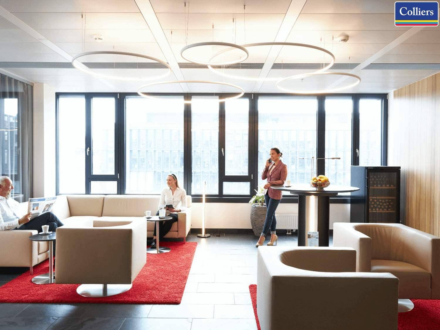 Heller und moderner Loungebereich mit bequemen Sitzgelegenheiten, großen Fenstern und dekorativen Deckenleuchten.