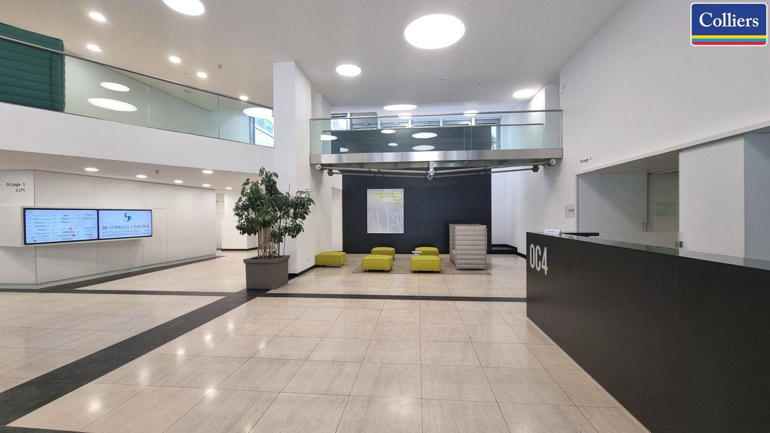 Geräumige und moderne Lobby mit Rezeption, Sitzgelegenheiten und Zugang zu oberen Etagen.