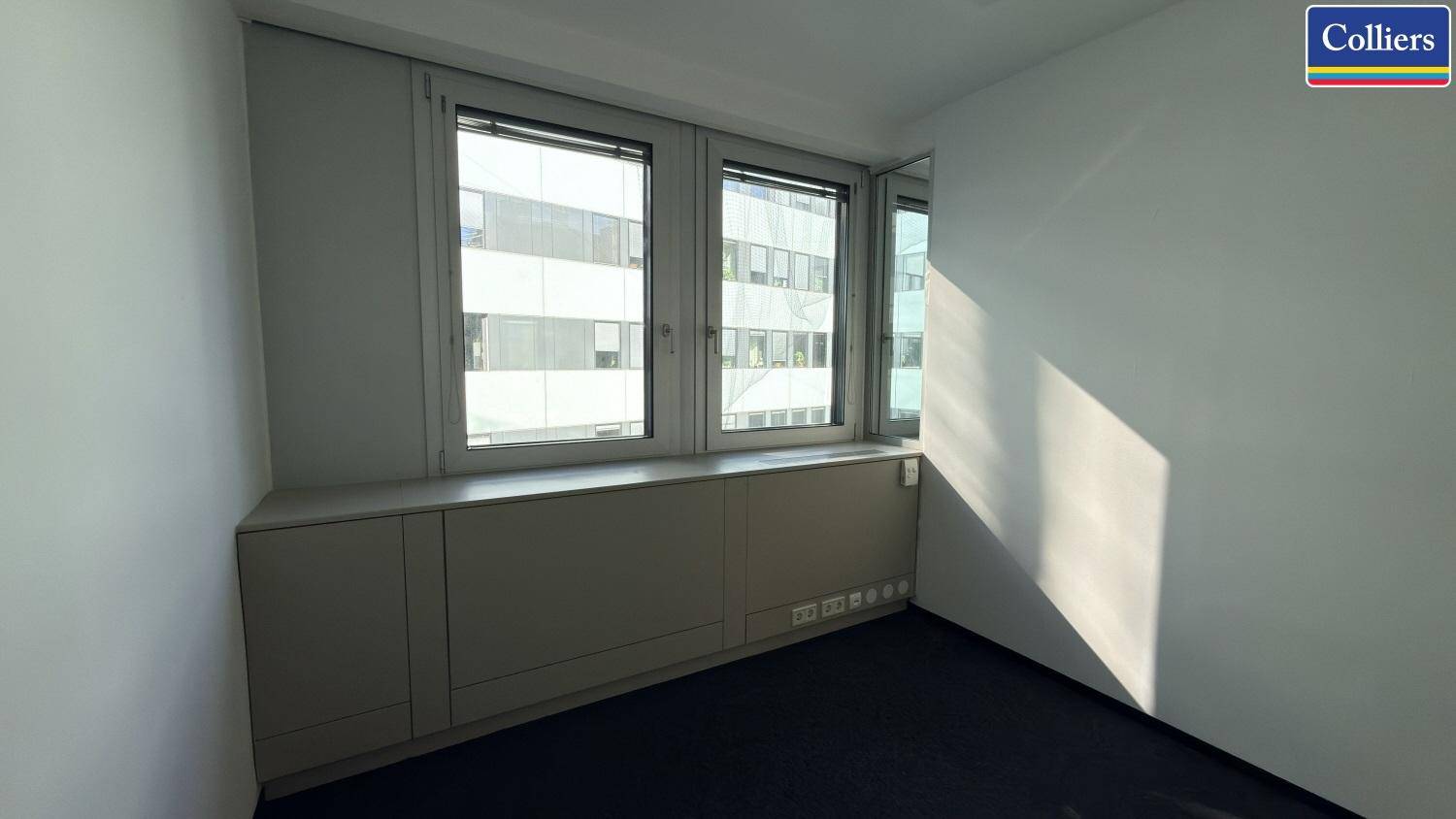 Helles Einzelbüro mit Teppichboden und breiter Fensterfront, bietet eine angenehme Arbeitsatmosphäre.