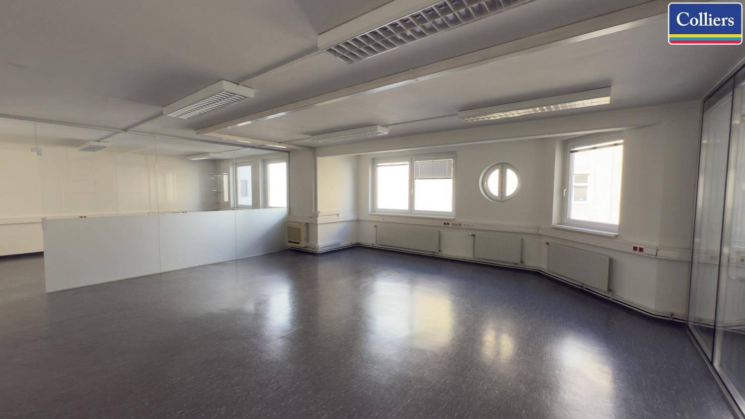 Geräumiges Büro mit großen Fenstern, runden Akzentfenstern und funktionaler Ausstattung, bereit zur individuellen Gestaltung.