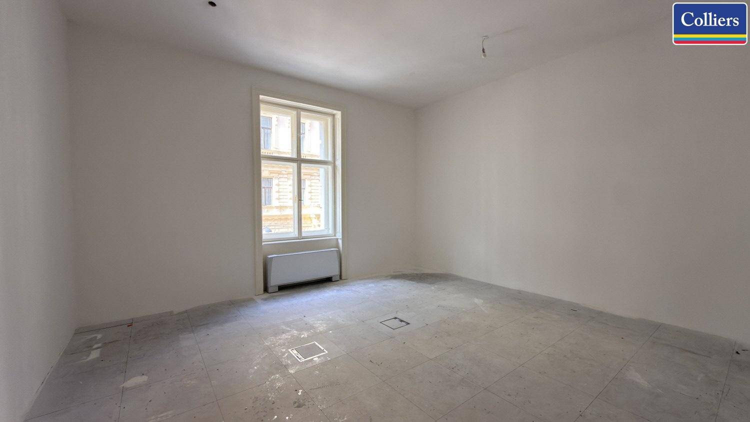 Leerer Büroraum mit einem großen Fenster und Heizkörper, der auf die Gestaltung wartet.