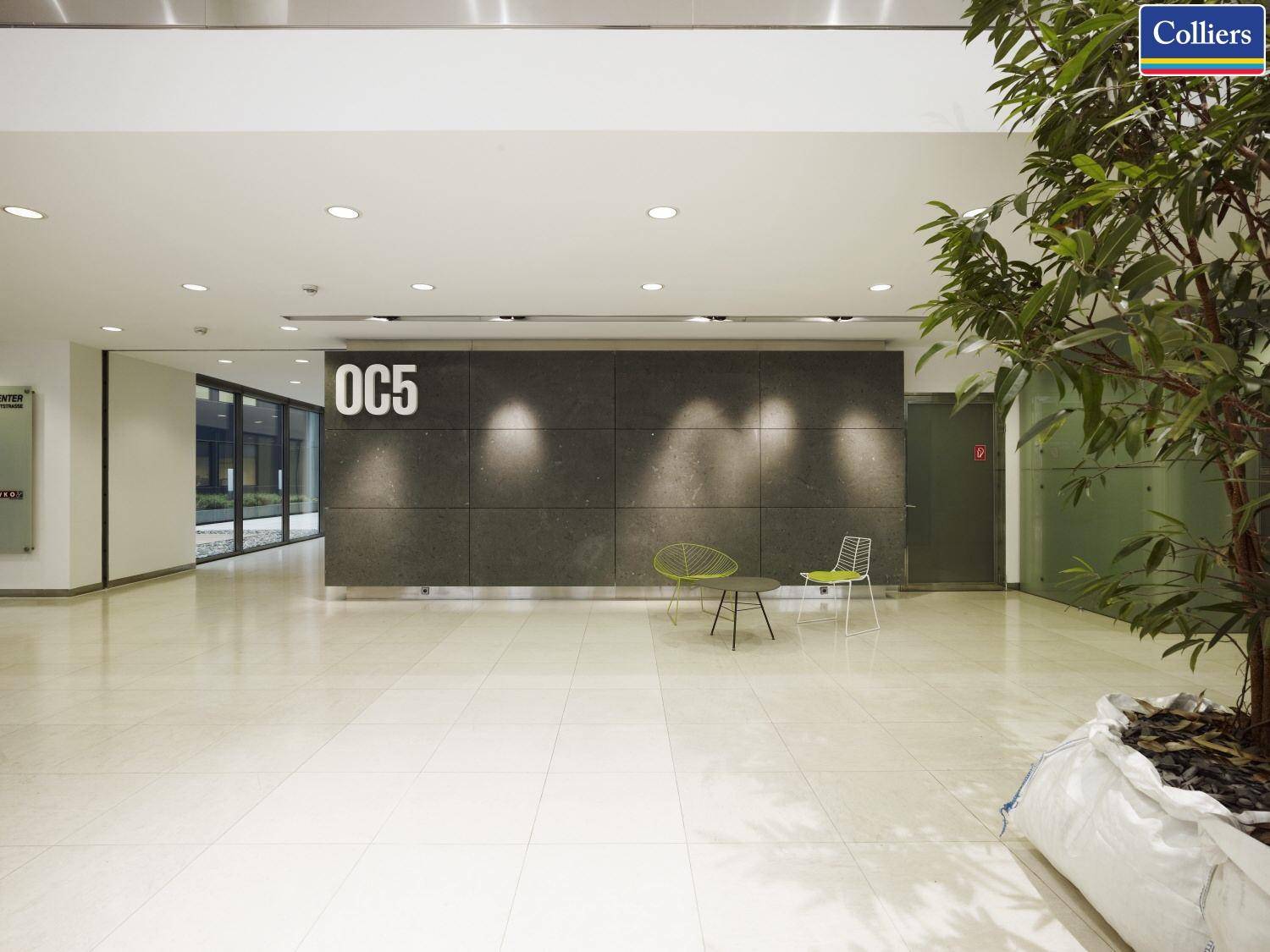 Moderne Lobby mit hellem Fliesenboden, dunkler Akzentwand und Sitzgelegenheiten.