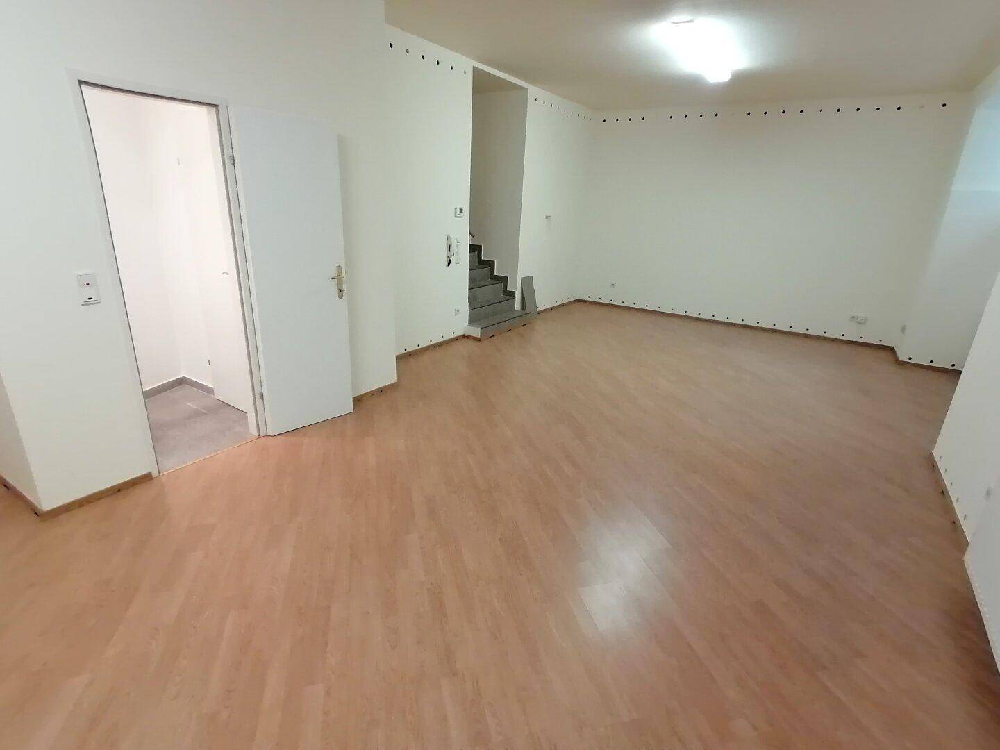 Großer, heller Raum mit Laminatboden und Treppenaufgang, bietet vielseitige Gestaltungsmöglichkeiten und ist gepflegt.