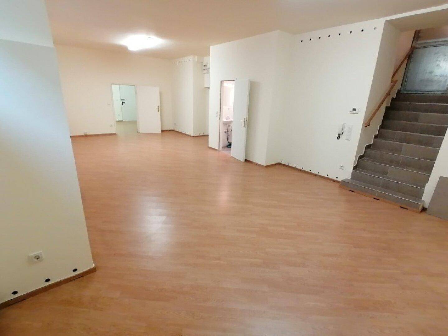 Großer, heller Raum mit Laminatboden und weiß gestrichenen Wänden, ideal für flexible Nutzung und Gestaltung.