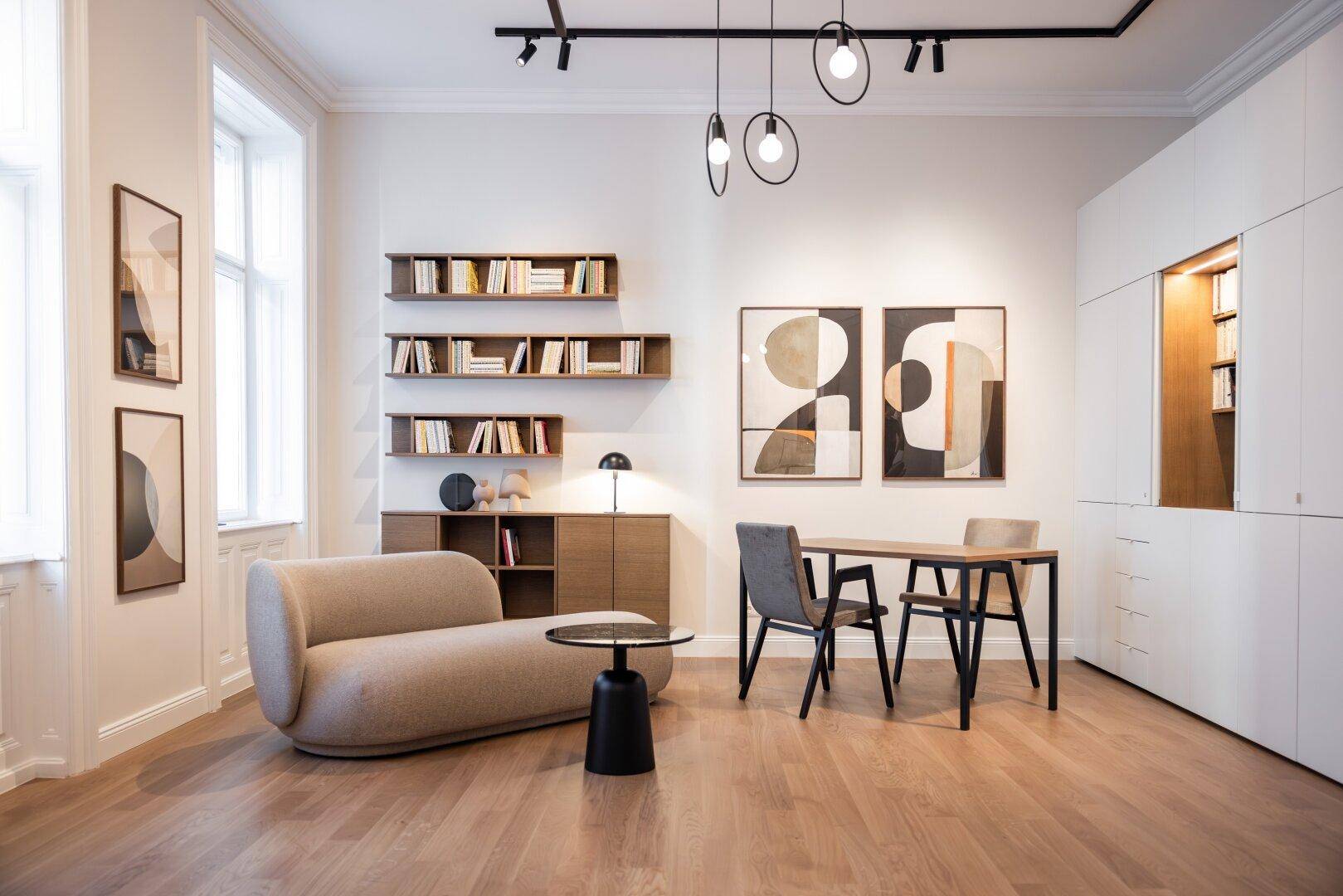 Vielseitiger Raum mit bequemer Couch, Esstisch, Bücherregalen und integrierten Schränken.