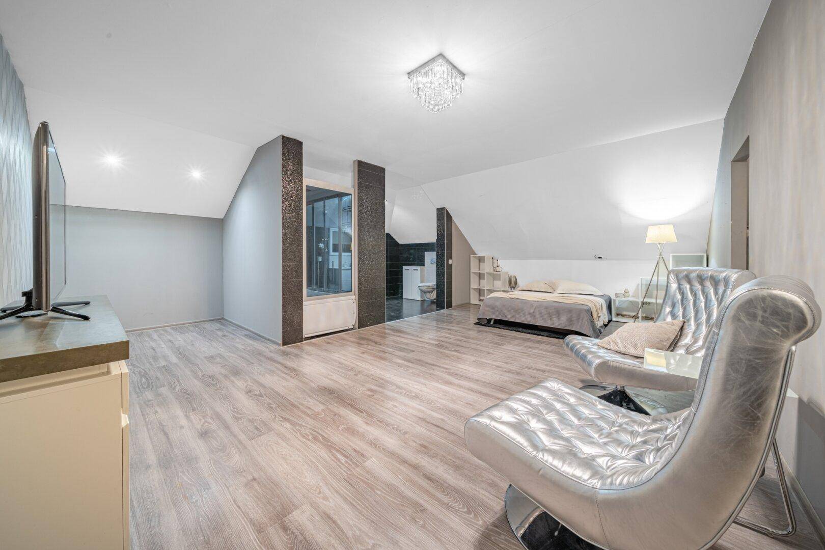Helles Schlafzimmer im Dachgeschoss mit Holzboden und modernen Möbeln.