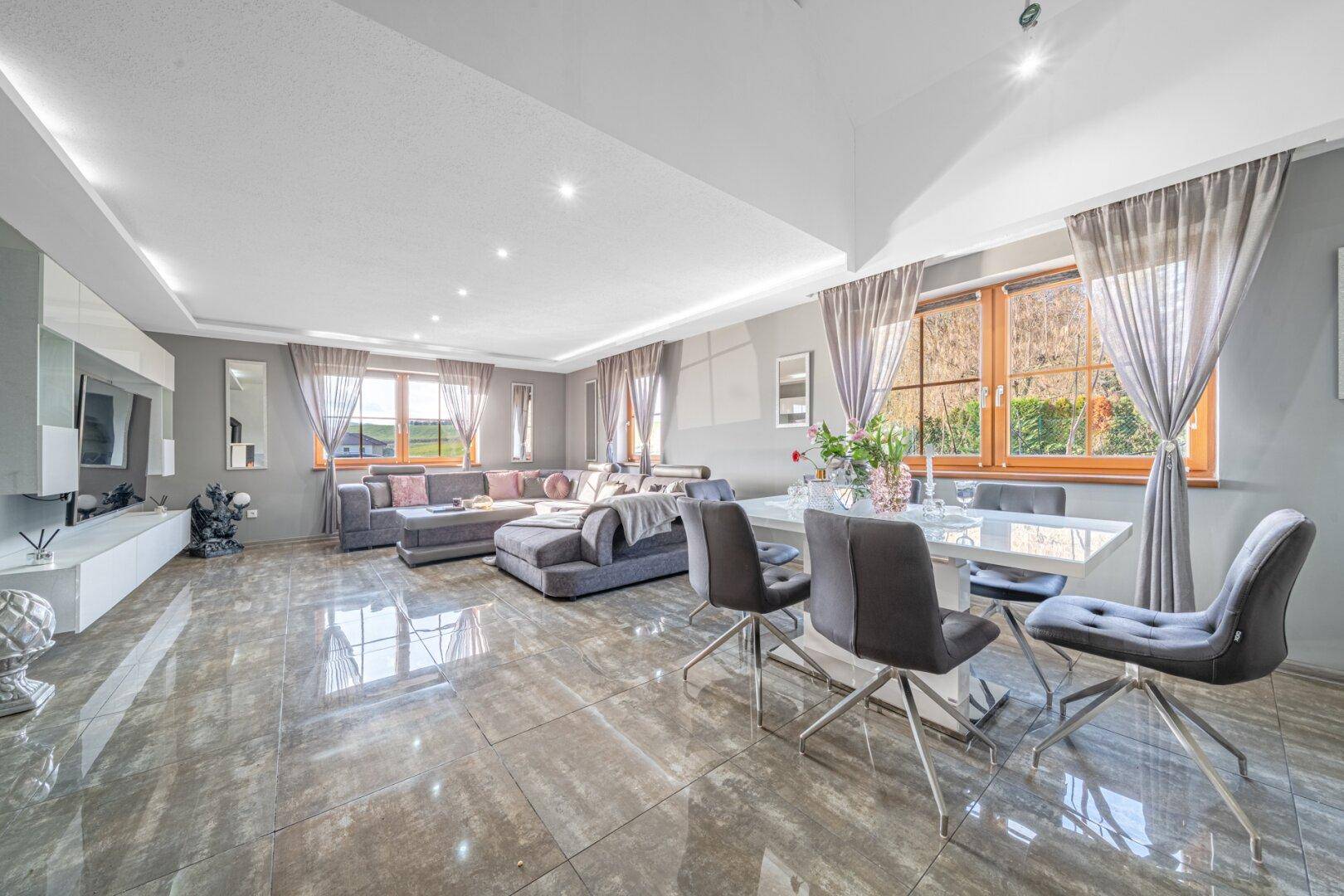 Geräumiger Wohn-Essbereich mit großem Sofa, Esstisch und glänzenden Fliesen.