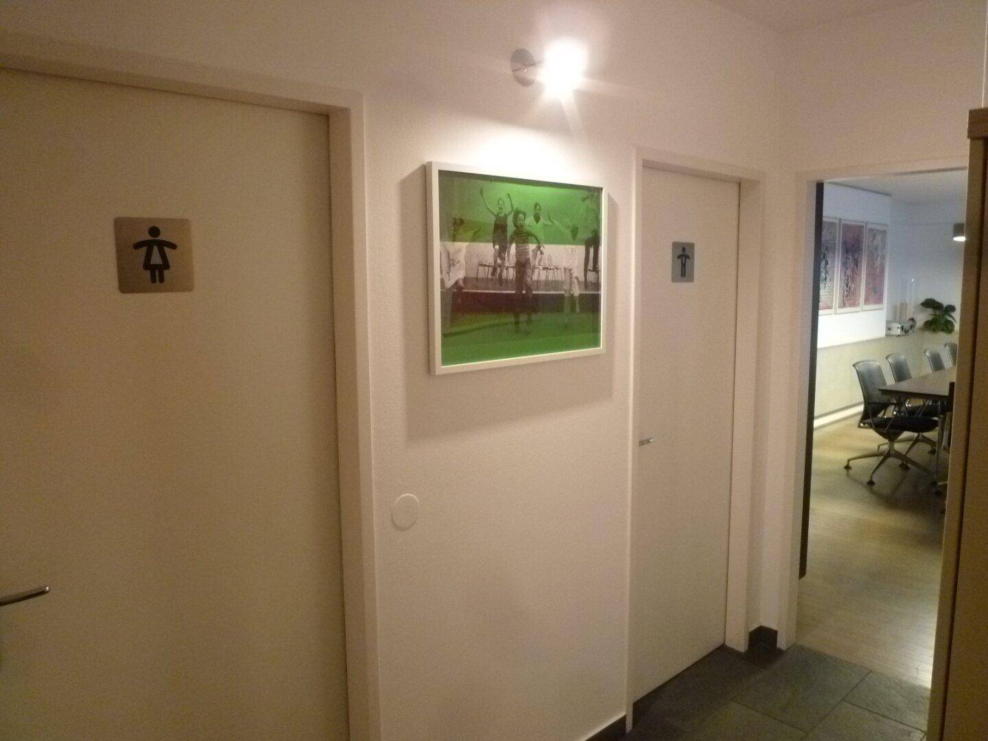 Heller Flur mit Türen zu den Toiletten und einem Blick in den Konferenzraum.