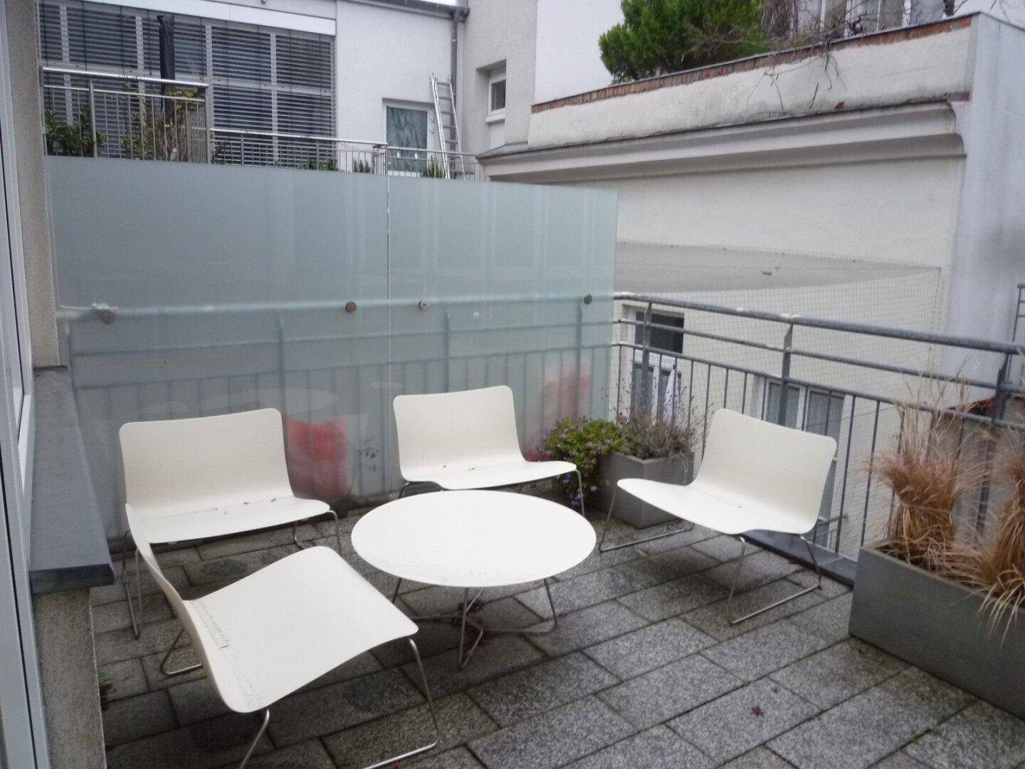 Kleiner Balkon mit modernen Gartenmöbeln und Blick auf die umliegenden Gebäude.