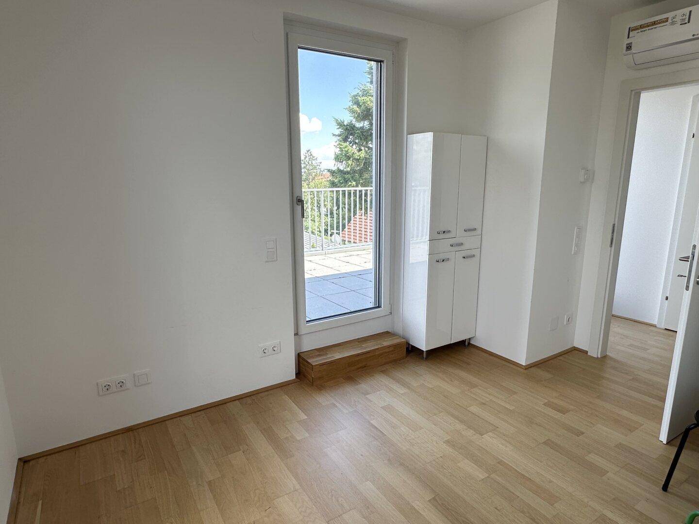 Helles Zimmer mit Holzboden und direktem Zugang zur großzügigen Dachterrasse.