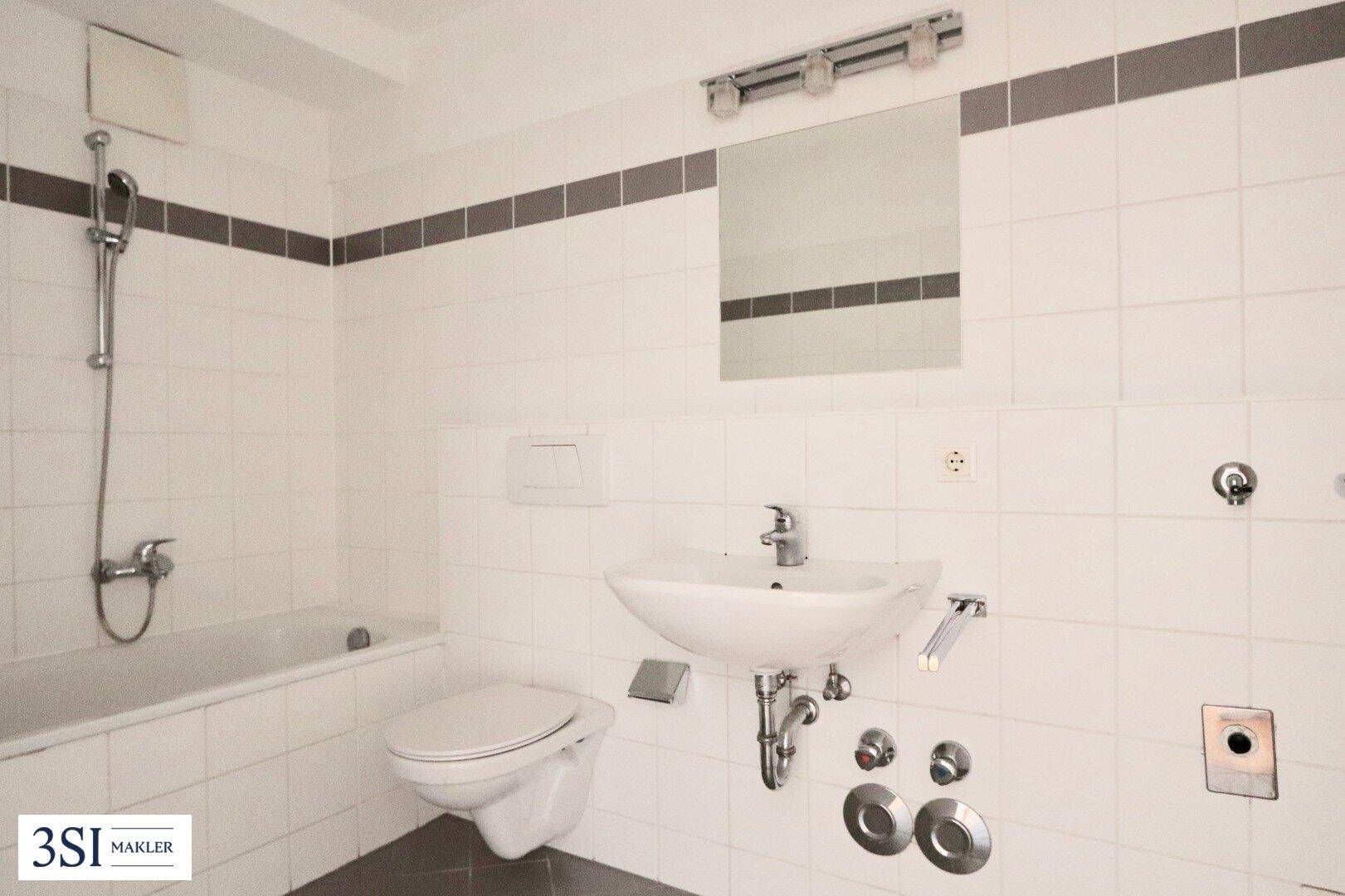Gefliestes Badezimmer mit Badewanne, Dusche, wandhängendem WC und Waschbecken.