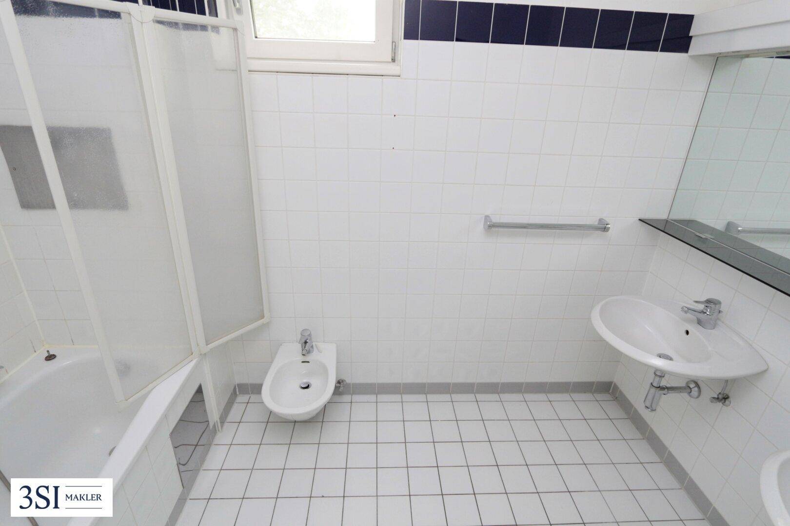 Badezimmer mit Badewanne, Dusche, Bidet und Waschbecken, ausgestattet mit weißen und blauen Fliesen.