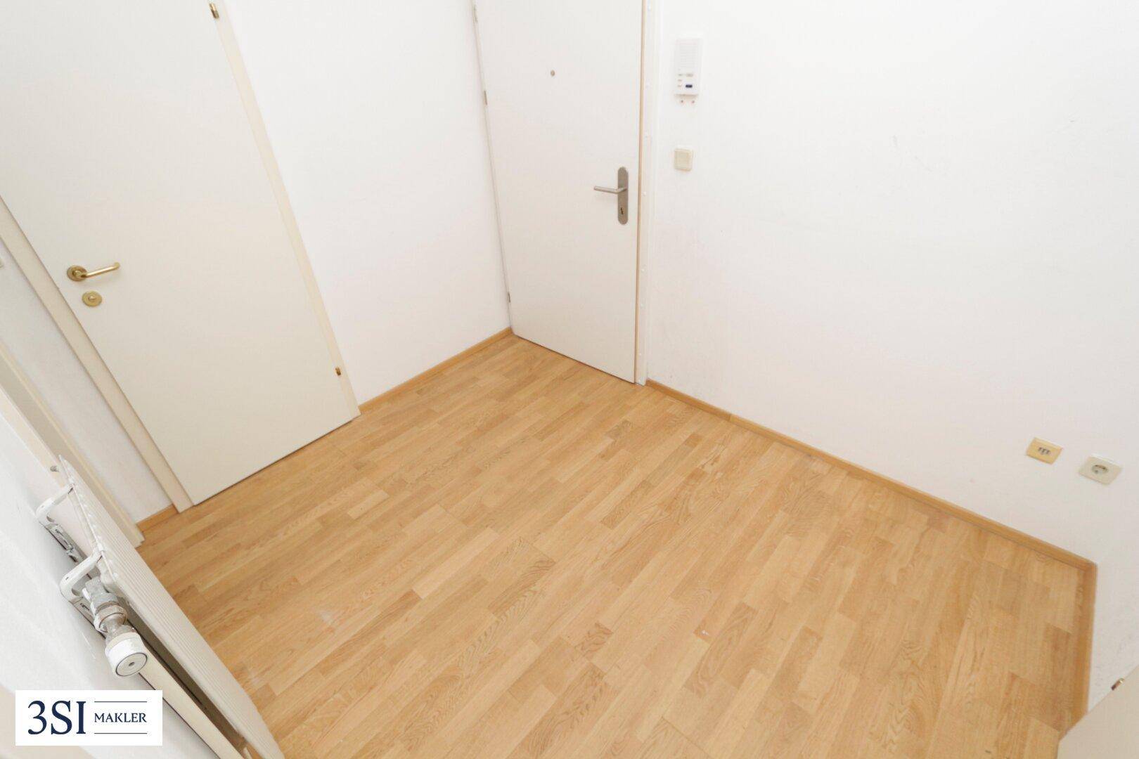 Heller Flurbereich mit Parkettboden und weißen Türen, der verschiedene Räume miteinander verbindet.