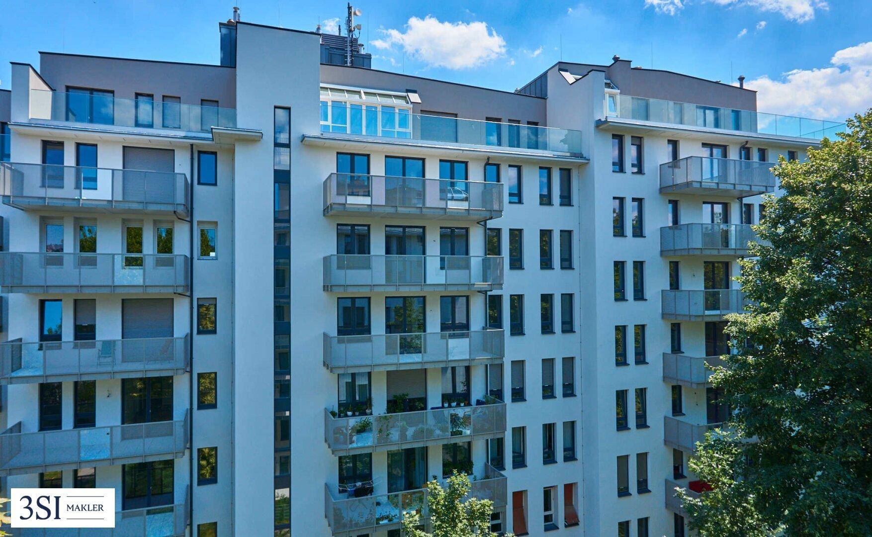 Ansicht der modernen Wohnfassade mit zahlreichen Balkonen und großen Fensterfronten.