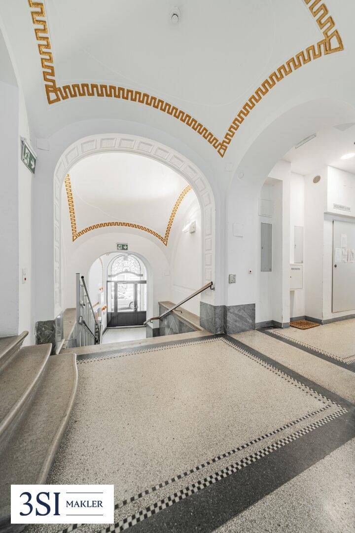 Historisches Treppenhaus mit kunstvollen Stuckverzierungen und Terrazzoboden.