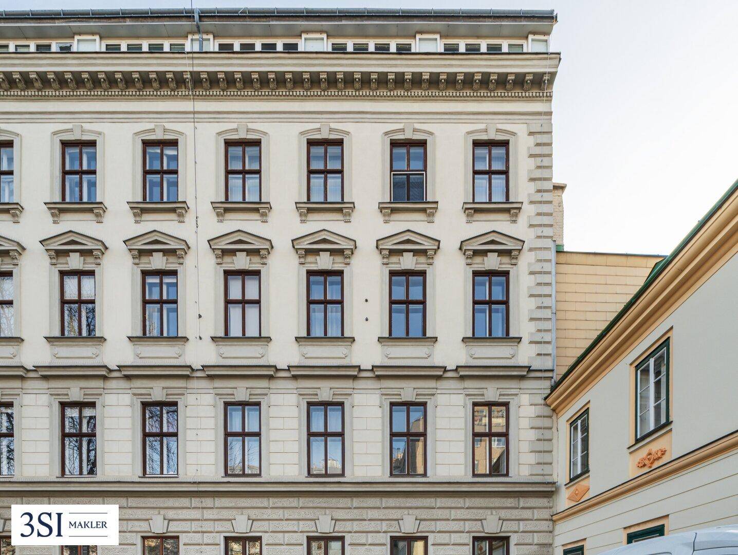 Detailansicht der historischen Fassade eines Altbaus mit vielen Fenstern.