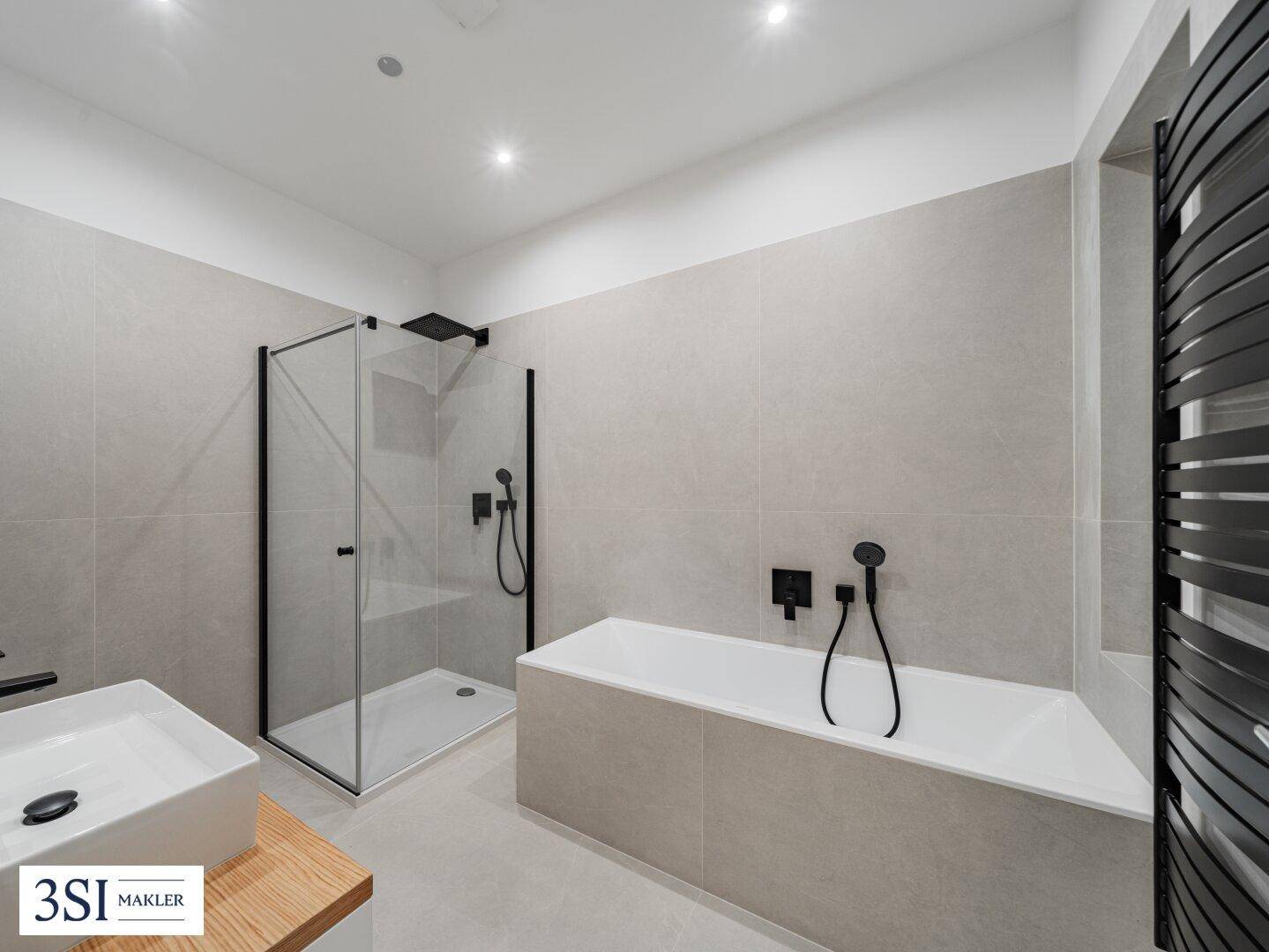 Modernes Badezimmer mit großer Badewanne, ebenerdiger Dusche und beheiztem Handtuchhalter.