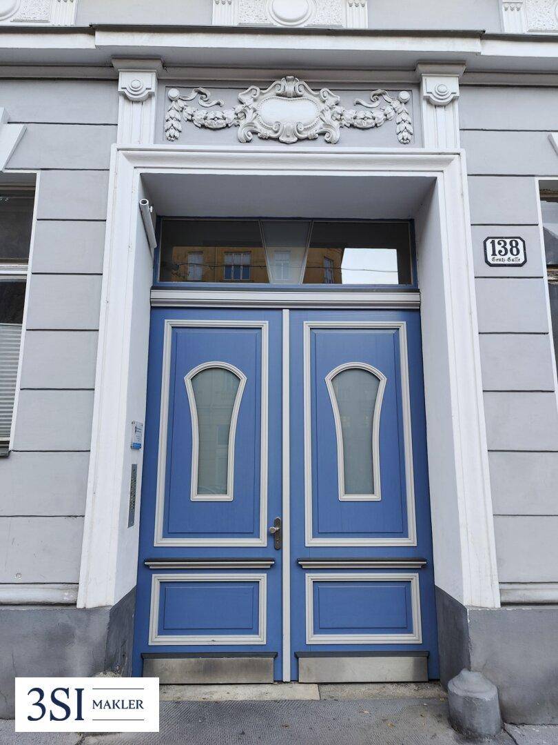 Frontale Ansicht der prächtigen blauen Eingangstür mit kunstvollen Stuckelementen und der Hausnummer.