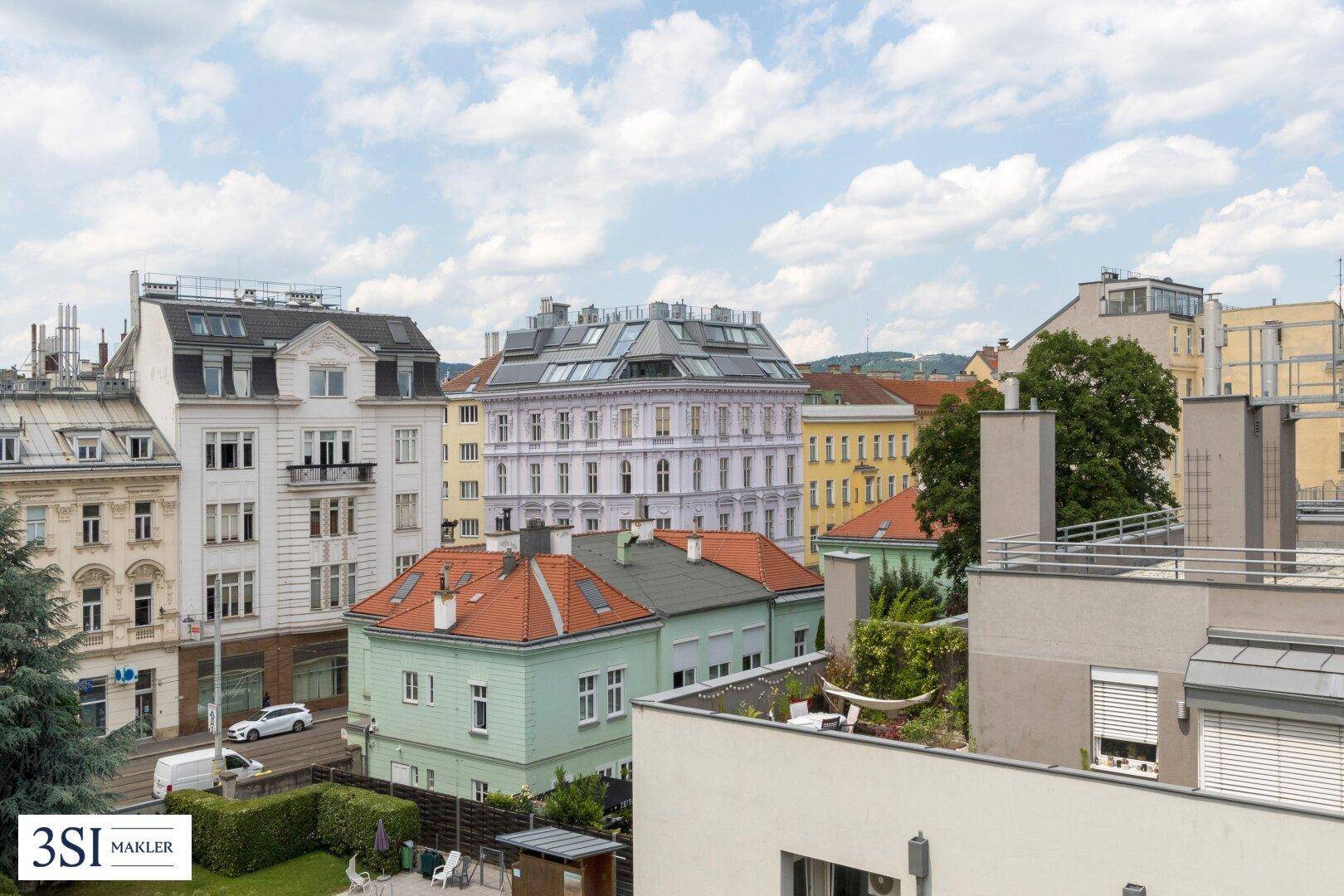 Weitläufiger Stadtblick über Dächer und Gebäude mit grünen Akzenten unter bewölktem Himmel.