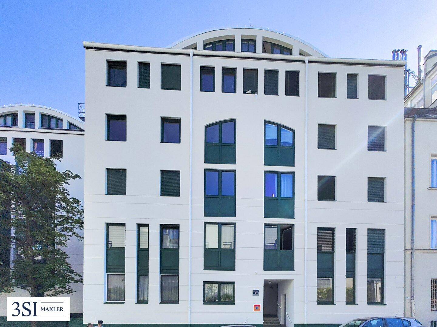 Ansicht der modernen Gebäudefassade mit vielen Fenstern und grünen Akzenten.