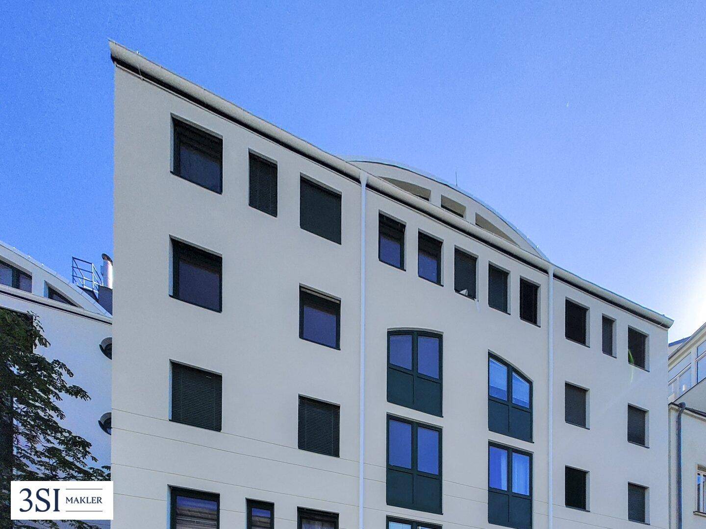 Seitenansicht der modernen Wohnanlage mit markanter Architektur und vielen Fenstern.
