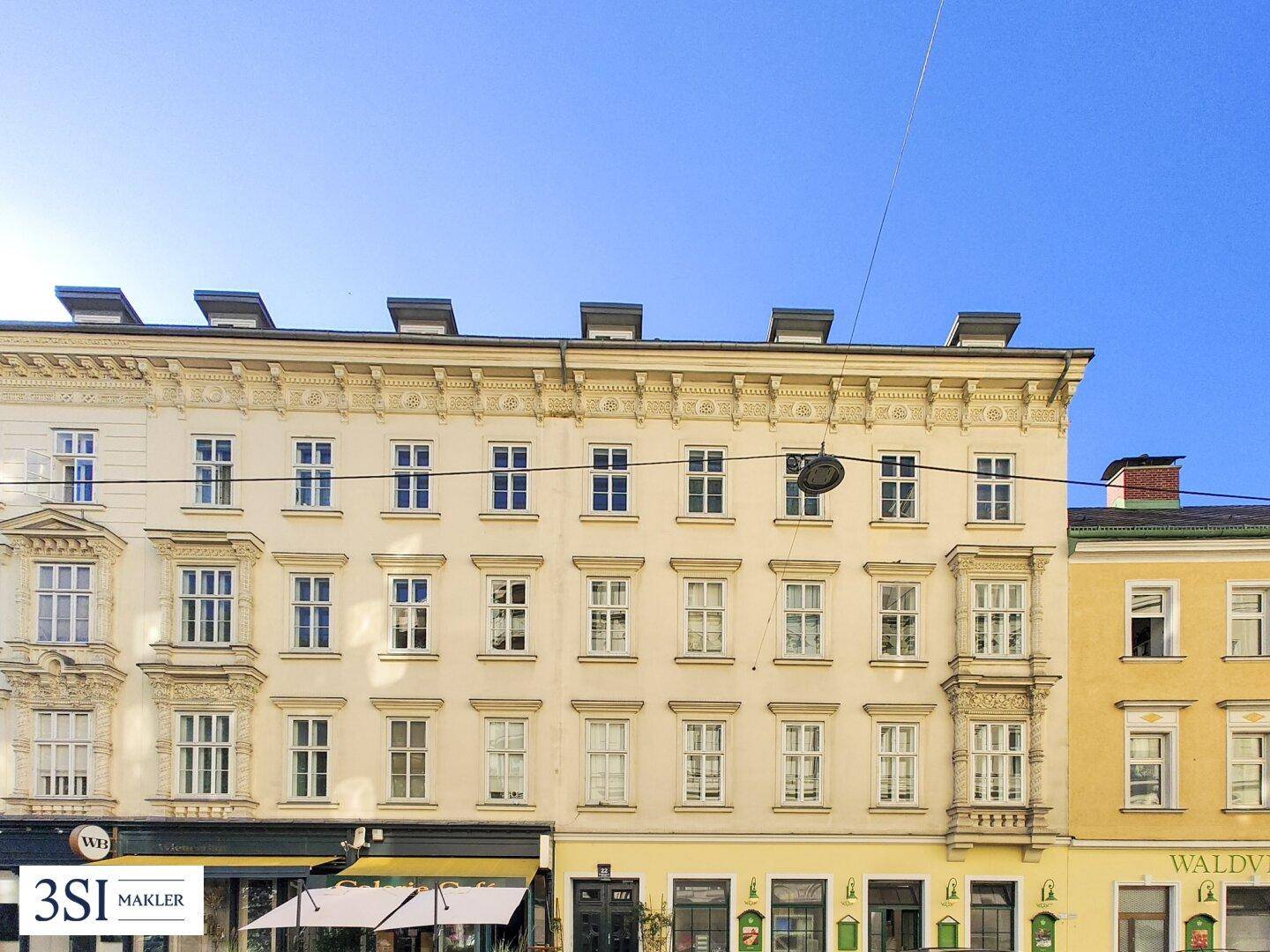 Klassische Fassade eines Mehrfamilienhauses mit vielen Fenstern und dekorativen Elementen.