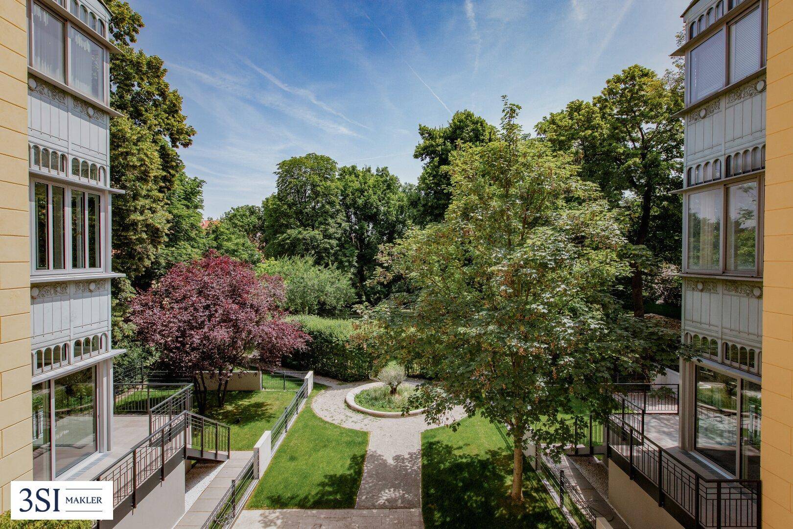Gepflegter Gartenbereich mit Bäumen, Wegen und angrenzenden Gebäudeteilen.