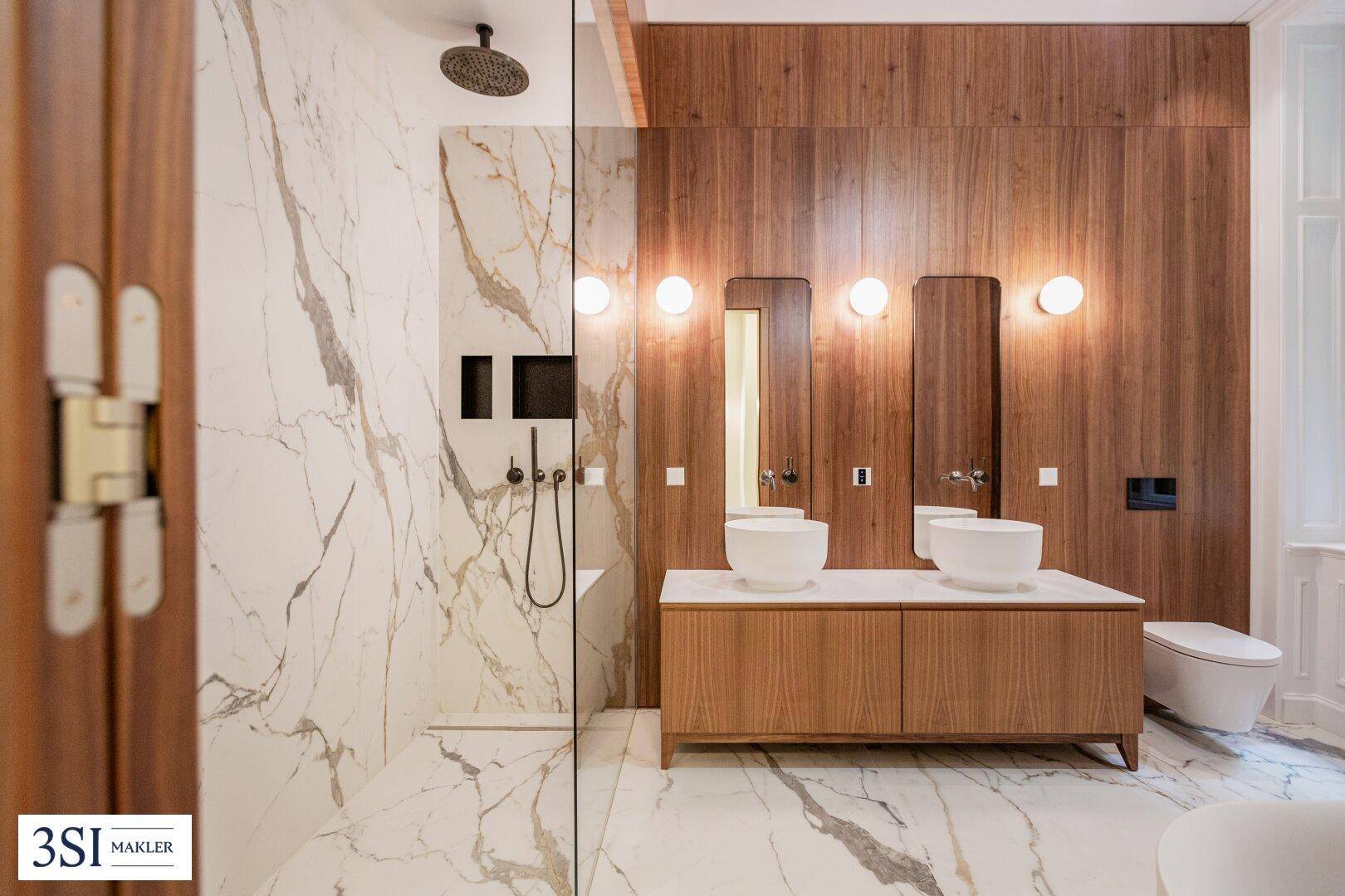 Luxuriöses Badezimmer mit Doppelwaschbecken, begehbarer Dusche und Marmorwänden.
