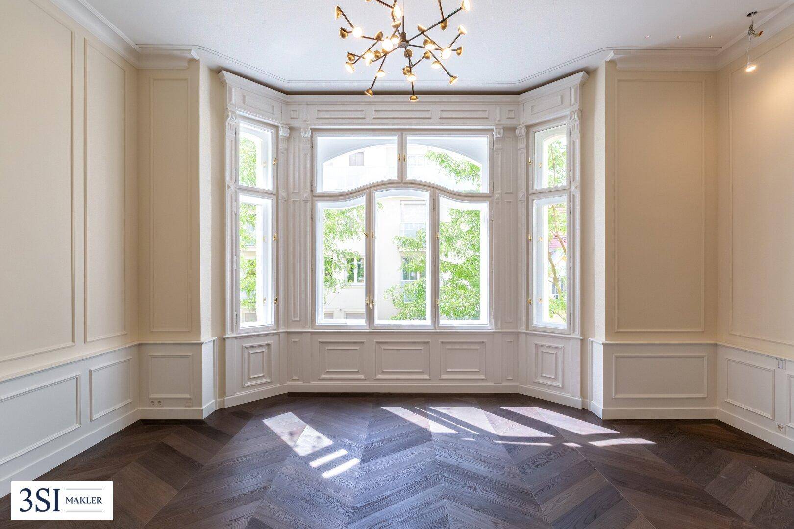 Elegantes Wohnzimmer mit Erkerfenster, dunklem Parkett und stilvoller Deckenbeleuchtung.