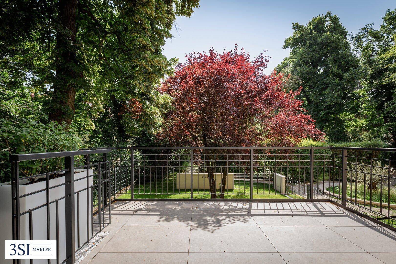 Geräumige Terrasse mit Metallgeländer und weitem Blick auf den grünen Garten.