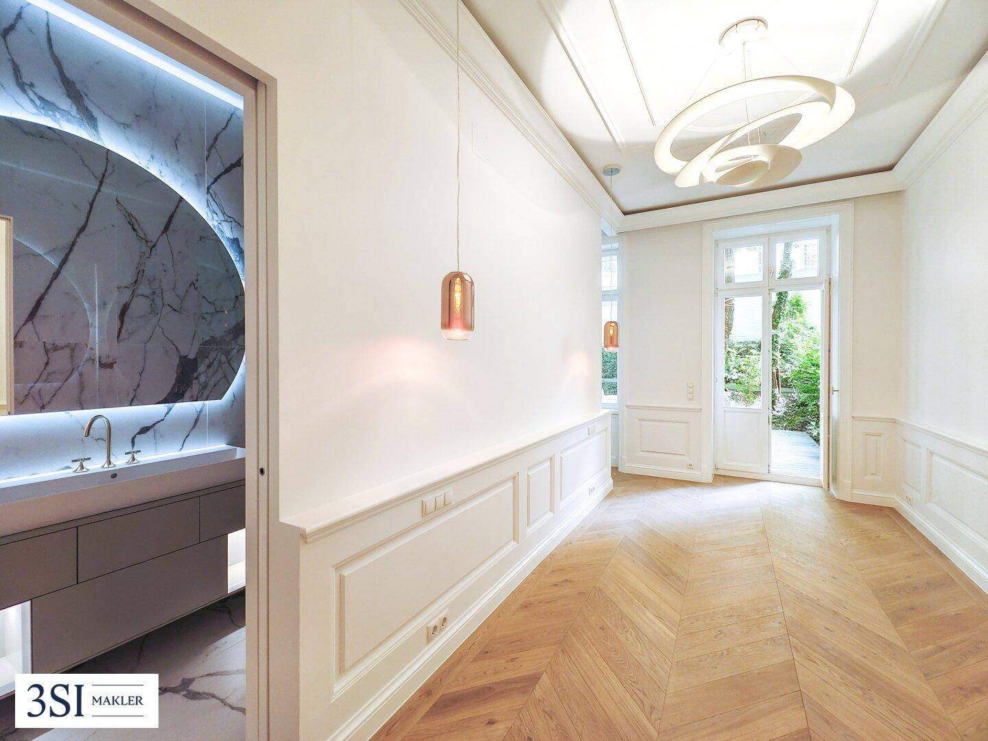 Heller Eingangsbereich mit Fischgrätparkett, hohen Decken und Zugang zu einem luxuriösen Badezimmer.