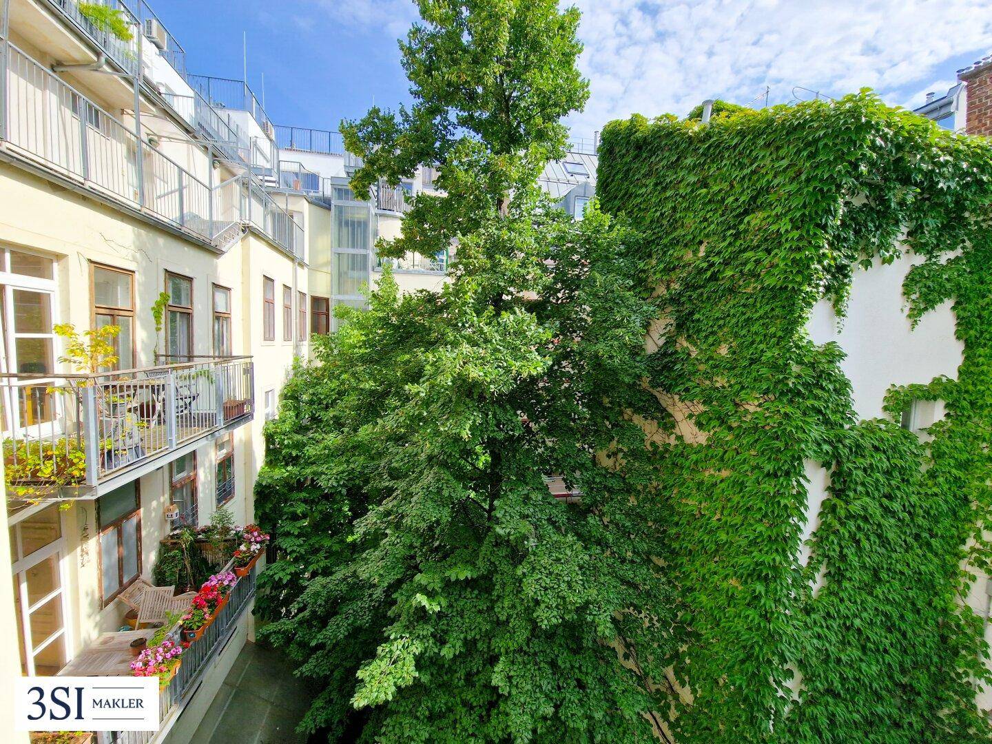 Blick auf begrünte Fassaden und Balkone im ruhigen Innenhof mit üppiger Vegetation.