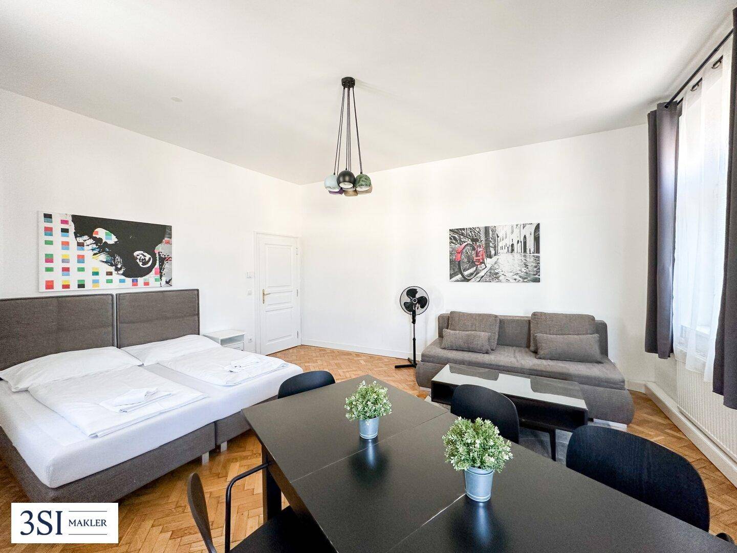 Helles, kombiniertes Wohn- und Schlafzimmer mit Esstisch, Sofa und Doppelbett in modernem Stil.