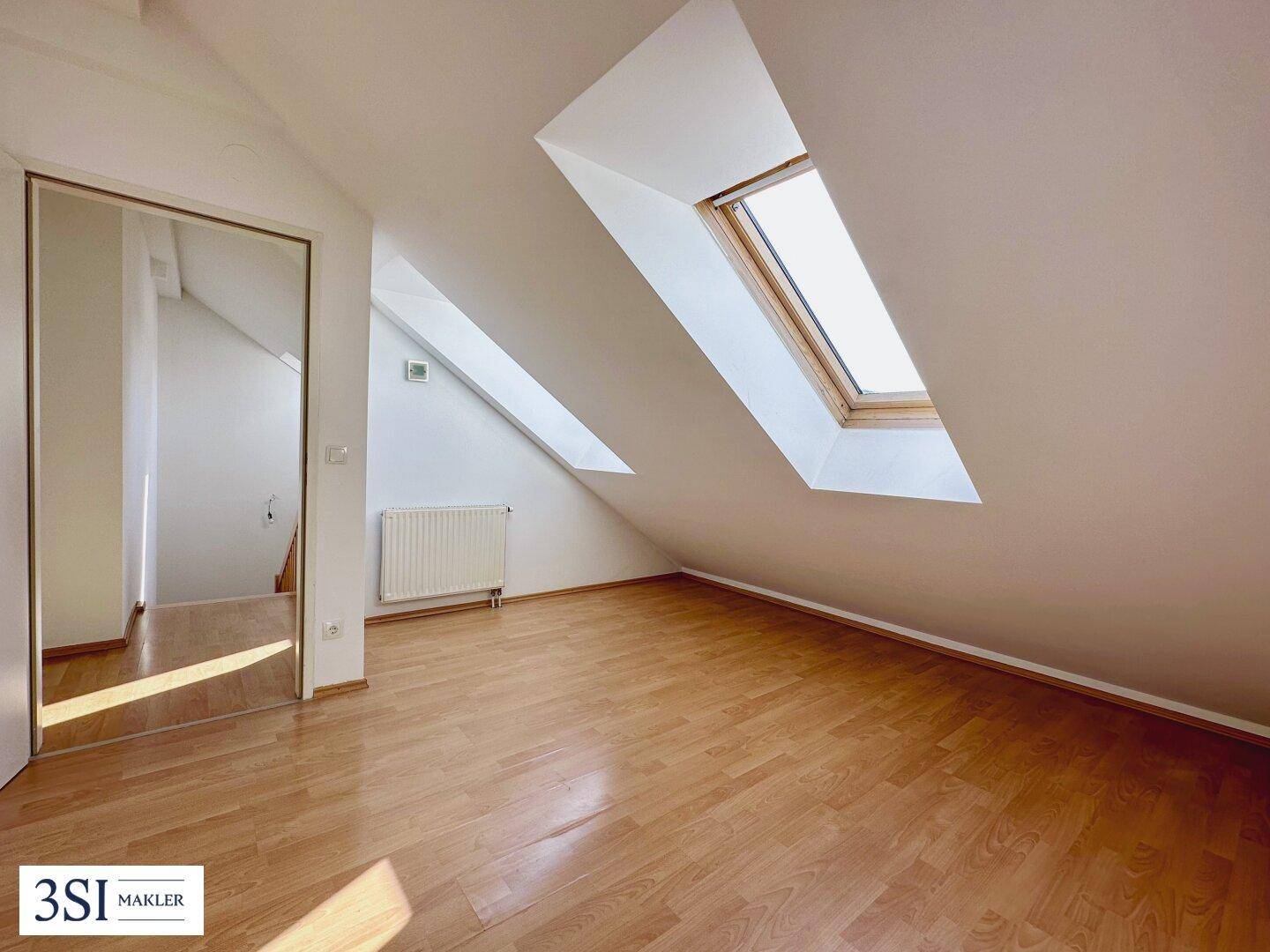 Heller Dachbodenraum mit schrägen Wänden, Dachfenstern und Laminatboden, ideal als Schlaf- oder Arbeitszimmer.