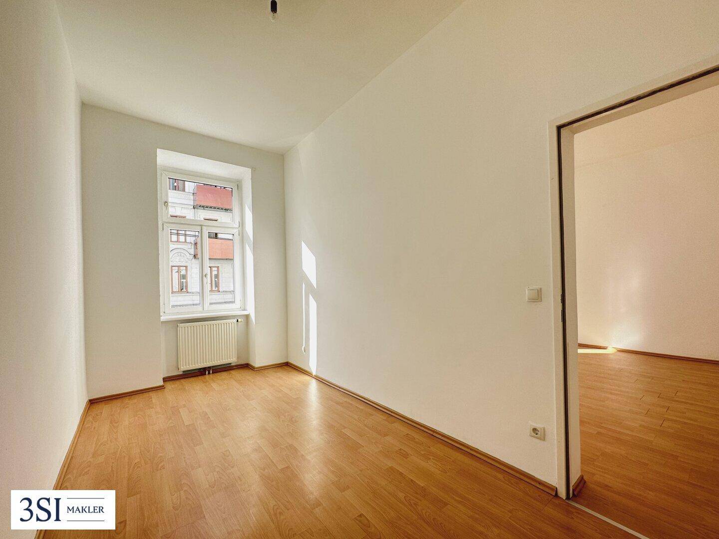 Heller Raum mit Parkettboden und weiß gestrichenen Wänden, ideal als Wohn- oder Schlafzimmer.
