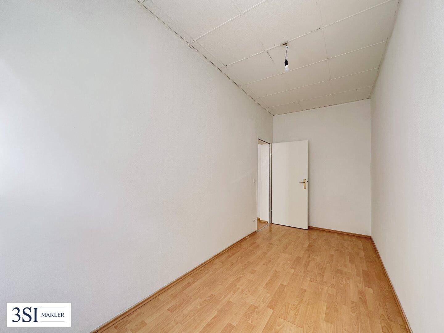 Leerer Raum mit hellem Laminatboden und weißen Wänden, bereit zur individuellen Gestaltung.