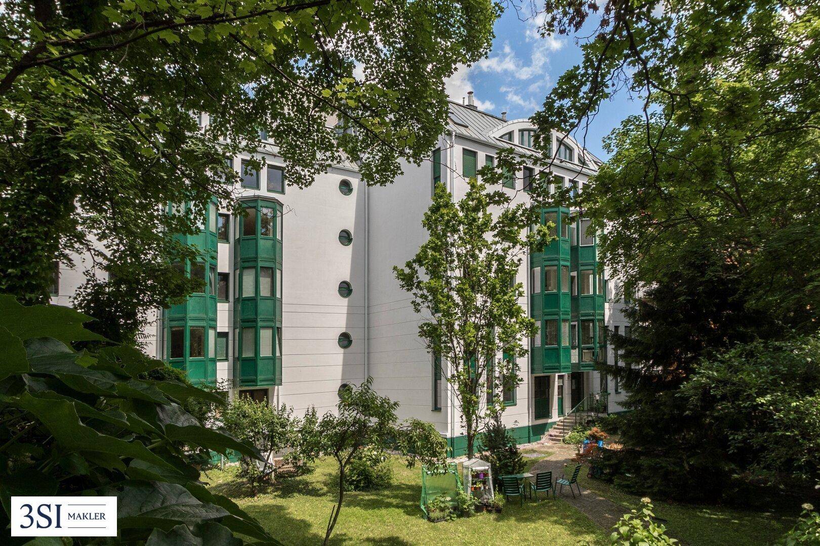 Grüner Innenhof mit Sitzgelegenheiten und Blick auf die moderne Gebäudefassade.