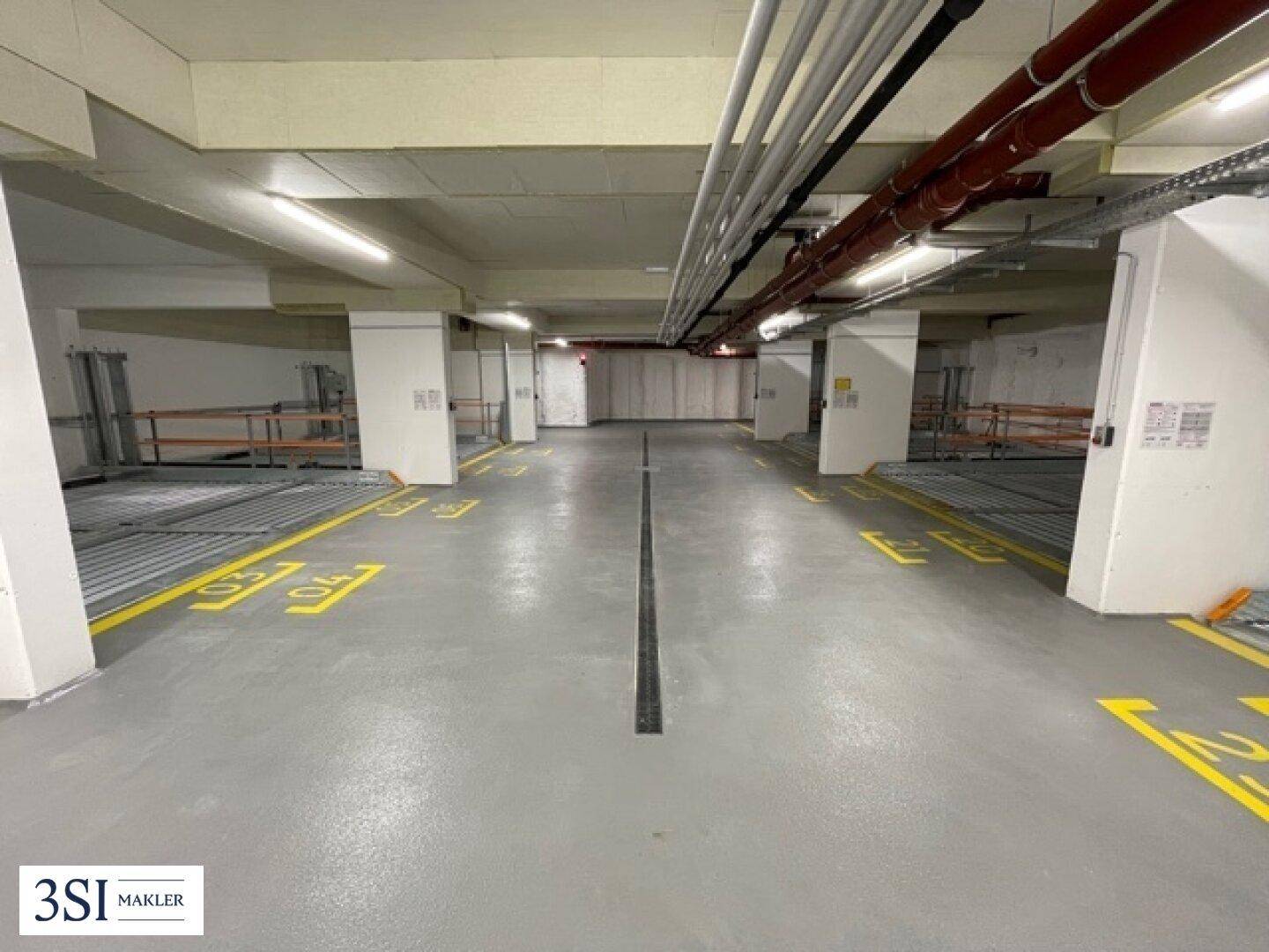Geräumige Tiefgarage mit mehreren Parkplätzen und klaren Fahrbahnmarkierungen.