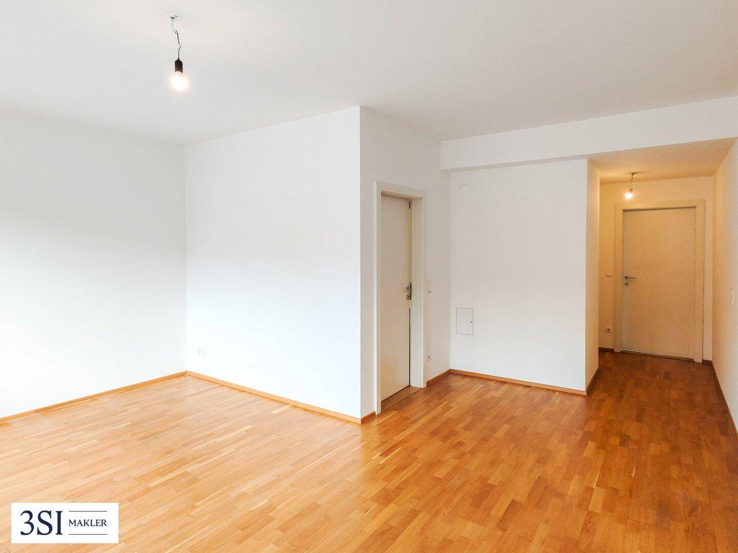 Geräumiges Zimmer mit Holzboden und Zugang zu weiteren Räumen, bietet vielseitige Nutzungsmöglichkeiten.