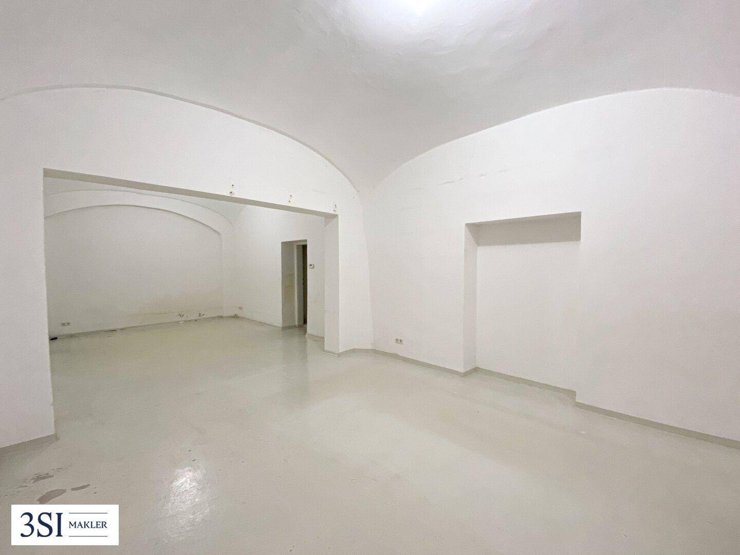 Geräumiger, leerer Innenraum mit gewölbter Decke, weiß gestrichenen Wänden und einer Nische.
