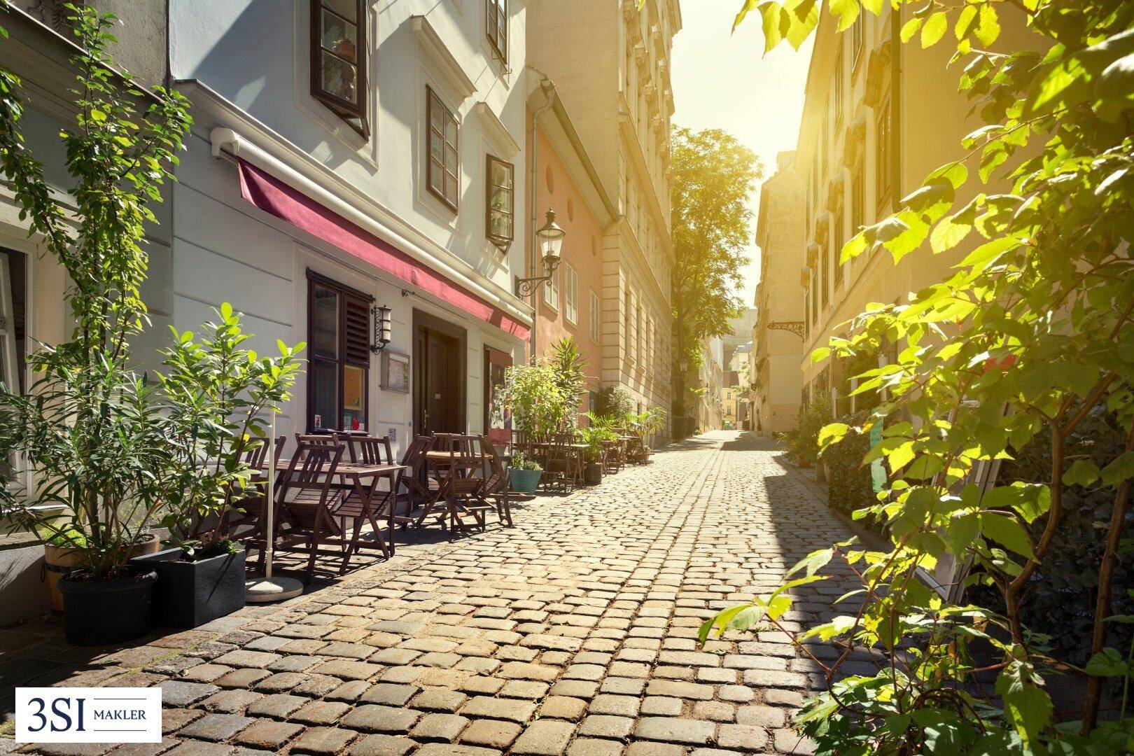 Charmante Kopfsteinpflastergasse mit Straßencafés und sonniger Atmosphäre in der Altstadt.