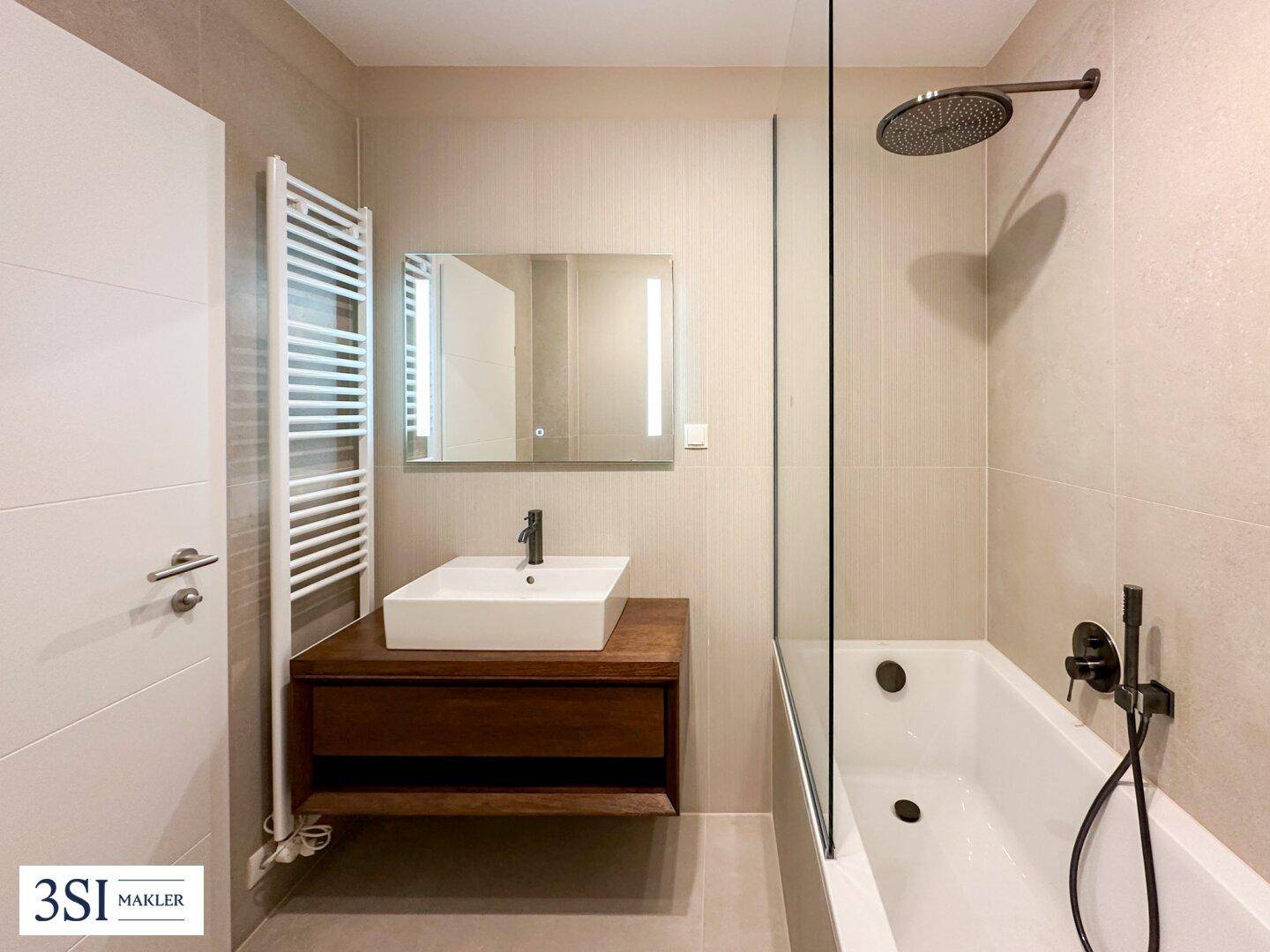 Modernes Badezimmer mit Badewanne, Regendusche, beheiztem Handtuchhalter und stilvollem Waschtisch.