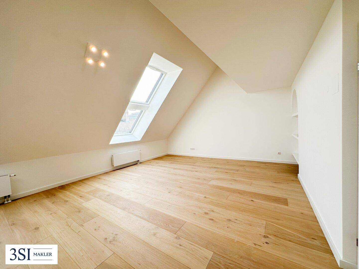 Geräumiges Zimmer mit Dachschräge, Holzparkettboden und großem Dachfenster, ideal als Schlafzimmer.