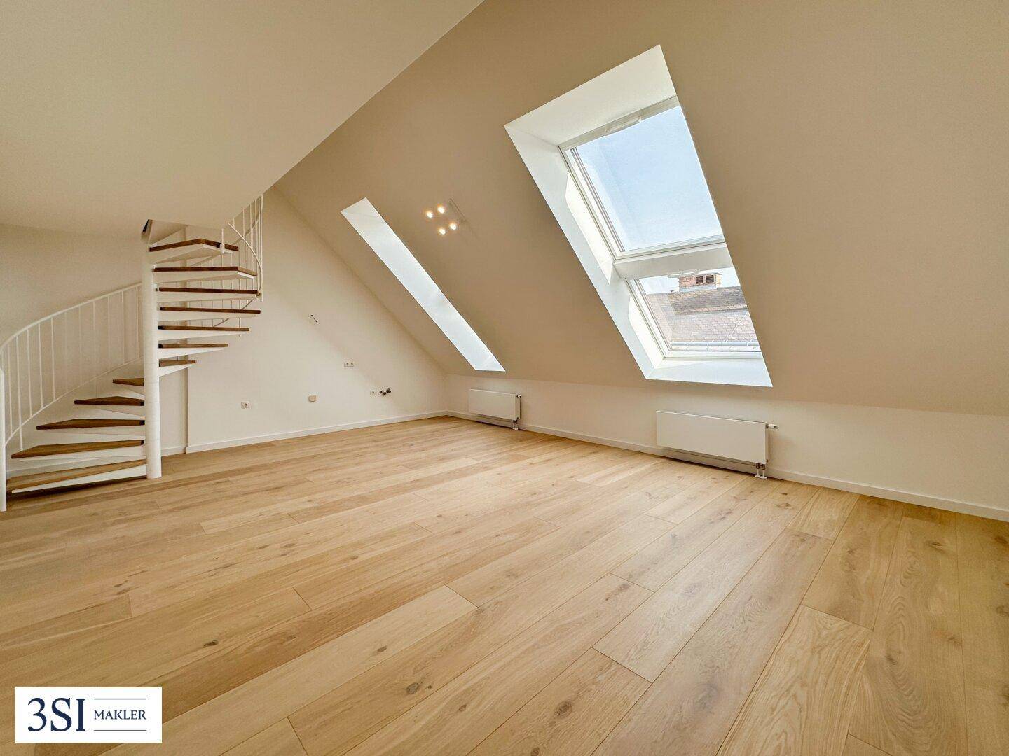 Heller Dachgeschossraum mit Holzfußboden, großen Dachfenstern und einer eleganten Wendeltreppe.