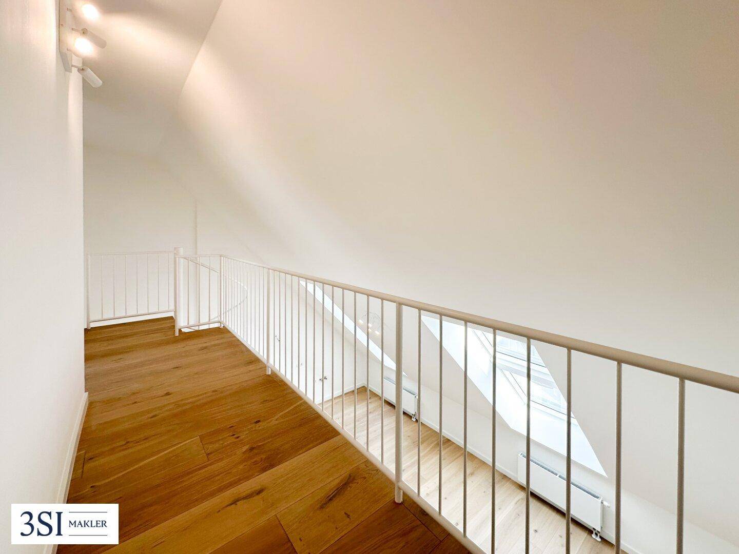 Heller Galeriebereich im Obergeschoss mit Blick auf die Dachschräge, Holzparkettboden und natürlichem Licht.