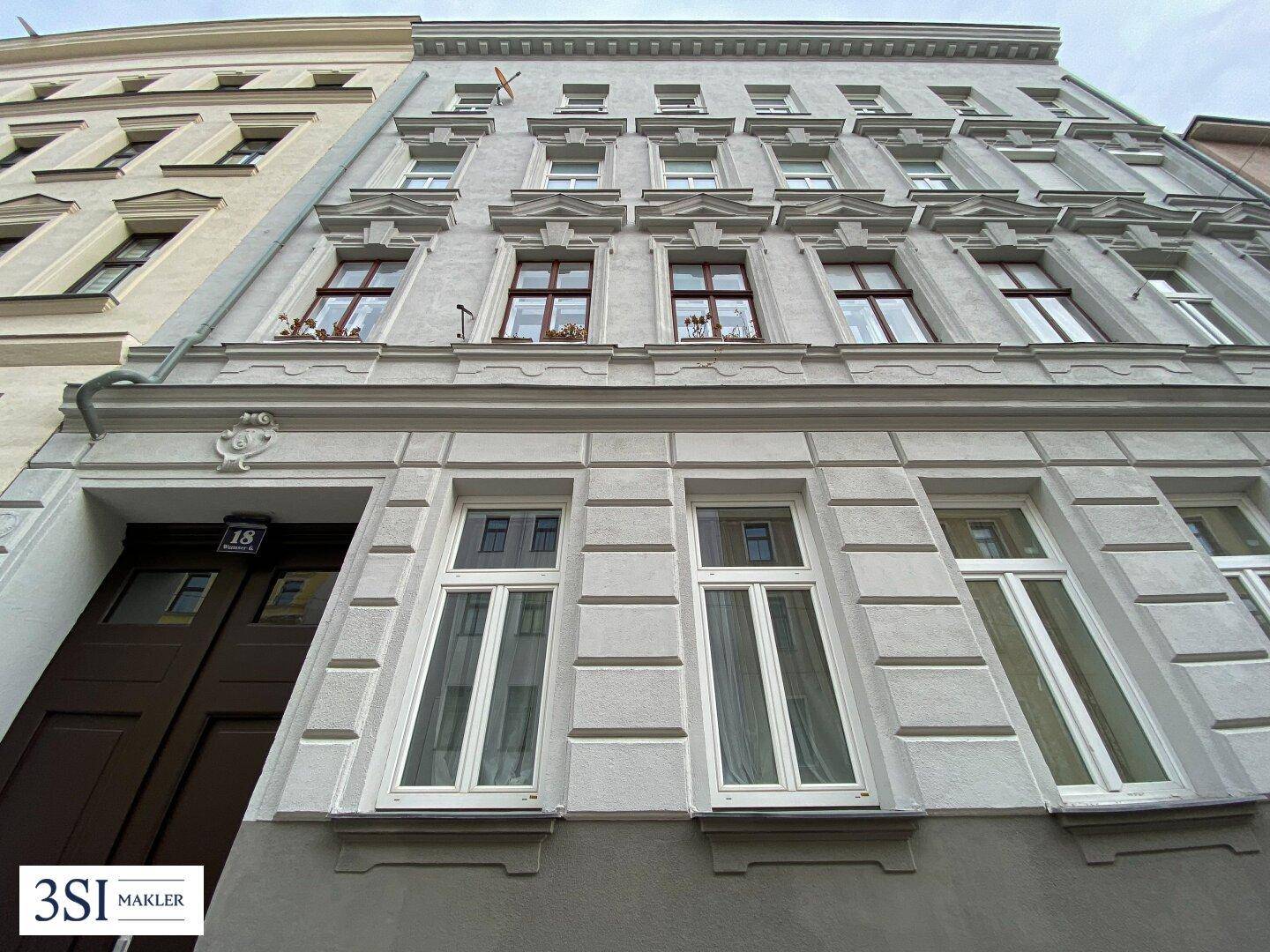 Detailansicht der historischen Fassade eines Altbaus mit verzierten Fensterrahmen und Eingangsbereich.