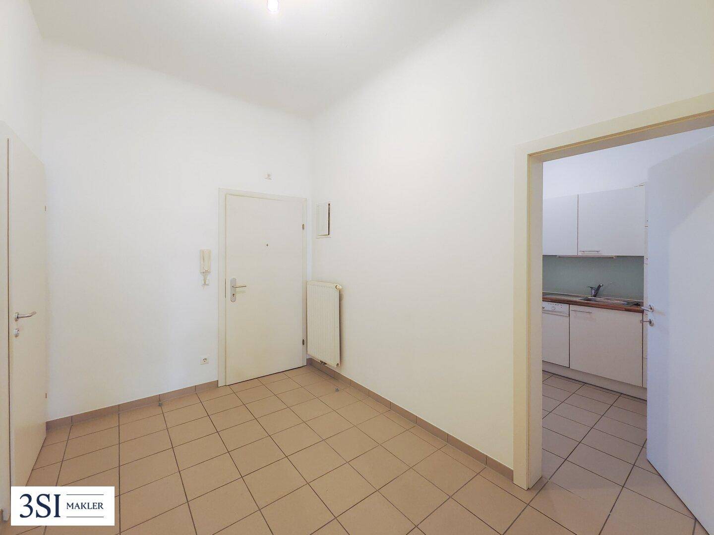 Heller Eingangsbereich mit Fliesenboden und Blick in die Küche.
