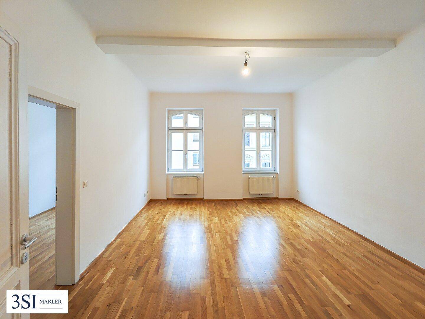 Geräumiges, helles Zimmer mit Holzboden und hohen Decken.